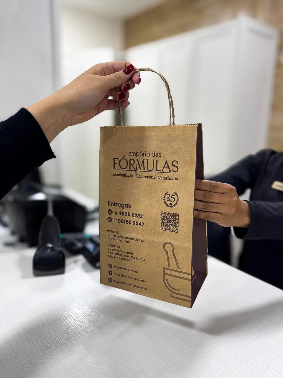 Atendente entregando sacola do Empório das Fórmulas ao cliente